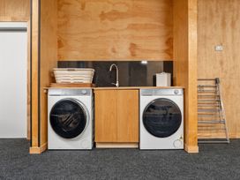 A laundry room with a washing machine, dryer, sink, and drying rack at Helmstead Cottage - Arrowtown
