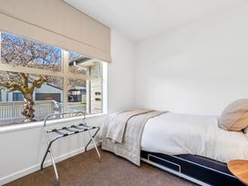 A bedroom with a bed and a drying rack at Helmstead Cottage - Arrowtown