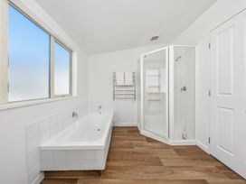 A bathroom with a bathtub and shower at Helmstead Cottage - Arrowtown