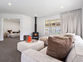 A living room with a stove and seating area at Helmstead Cottage - Arrowtown