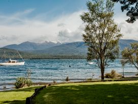 A view of a boat on the water with mountains and trees at Little Blue House - Te Anau