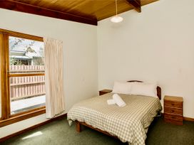 A bedroom with a bed and nightstand at Little Blue House - Te Anau