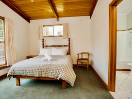 A bedroom with a bed and chair at Little Blue House - Te Anau