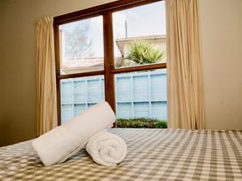 A bedroom with towels on a bed at Little Blue House - Te Anau