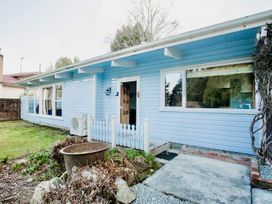 An exterior view of a blue house with a pathway and fenced area at Little Blue House - Te Anau