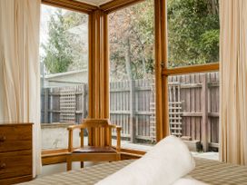 A bedroom with a wooden chair and window at Little Blue House - Te Anau