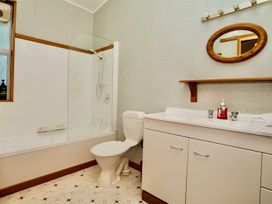 A bathroom with a bathtub, toilet, and sink at Little Blue House - Te Anau