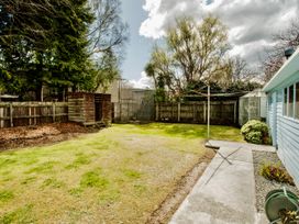 A garden with grass, trees, a shed, and a clothesline at Little Blue House - Te Anau