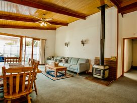 A living room with a table and chairs and a sofa at Little Blue House - Te Anau