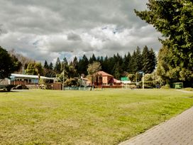 A view of a house and trees on a grassy area near a road at Little Blue House - Te Anau