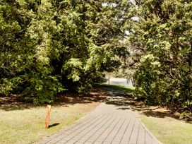 A pathway surrounded by trees leading to water at Little Blue House - Te Anau