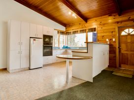 A kitchen with cabinets, oven, sink and table at Little Blue House - Te Anau