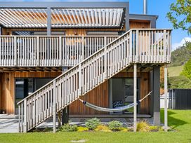 An outdoor area with a building, stairs, and a hammock at The Cove Escape - Cooks Beach