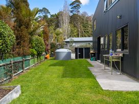 A garden with a water tank and table at The Cove Escape - Cooks Beach
