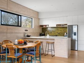 A kitchen with a dining table and chairs at The Cove Escape - Cooks Beach