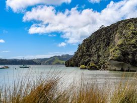A view of boats on water near a hill with trees at The Cove Escape - Cooks Beach