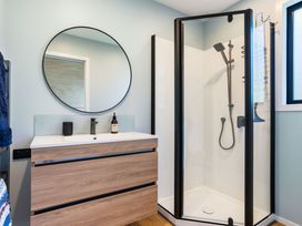 A bathroom with a shower and vanity at The Cove Escape - Cooks Beach