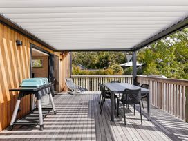 An outdoor space with a barbecue and a dining table at The Cove Escape - Cooks Beach
