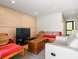 A living room with a television and sofa at The Cove Escape - Cooks Beach