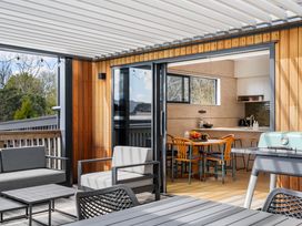 A patio with outdoor seating and a view of the kitchen at The Cove Escape - Cooks Beach