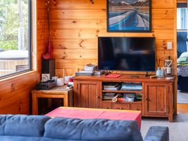 A living room with a television and wooden cabinet at Lakeside on Te Waaka - Kuratau