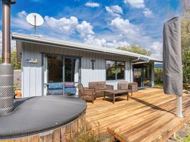 An outdoor seating area with a hot tub and wooden deck at Lakeside on Te Waaka - Kuratau