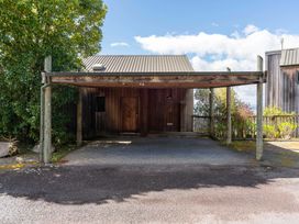 A carport with a wooden front door and pathway at Fern View - Pukawa Bay