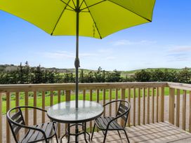 An outdoor area with a table and chairs under an umbrella at Over the Paddock - Waipu