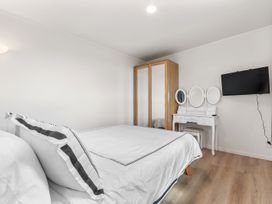 A bedroom with a bed, wardrobe, dressing table, and television at Over the Paddock - Waipu