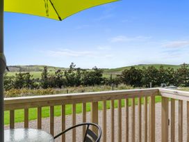 A view from a deck with an umbrella and furniture at Over the Paddock - Waipu