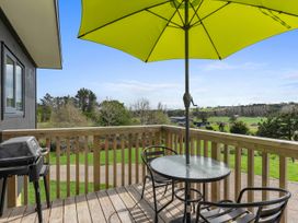 An outdoor deck with a table and chairs and a barbecue grill at Over the Paddock - Waipu