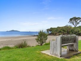 A bench facing the ocean at Over the Paddock - Waipu Holiday Home in Waipu