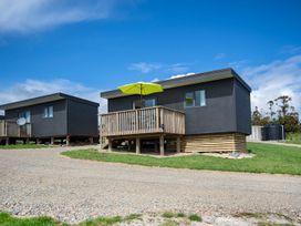 A house with a deck and umbrella at Over the Paddock - Waipu