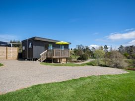 A cabin with a deck and umbrella at Over the Paddock - Waipu