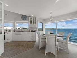 A dining room with a table and chairs overlooking the sea at Hampton Cottage by the Lake - Taupo Central