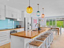 A kitchen with a kitchen island and bar stools at Waipu Hilltop Escape - Waipu Cove