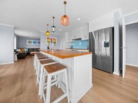 A kitchen with an island and bar stools at Waipu Hilltop Escape - Waipu Cove