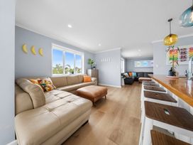 A living room with a sofa and bar stools at Waipu Hilltop Escape - Waipu Cove