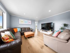 A living room with a sofa and television at Waipu Hilltop Escape - Waipu Cove