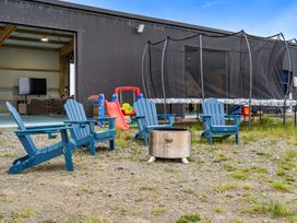 An outdoor area with blue adirondack chairs and a trampoline at Waipu Hilltop Escape - Waipu Cove