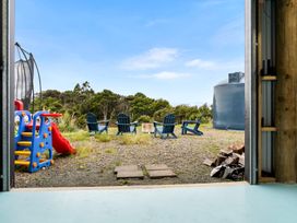 An outdoor area with a play structure and blue chairs at Waipu Hilltop Escape - Waipu Cove