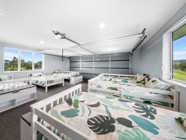 A bedroom with multiple beds and a garage door at Waipu Hilltop Escape - Waipu Cove