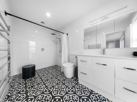 A bathroom with a shower, toilet, sink, and mirror at Waipu Hilltop Escape - Waipu Cove