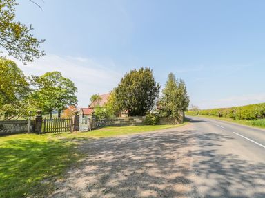 A rural road with hedges and trees next to a gate and stone wall of a house at Fenwick Retreat at Fenwick Lodge Fenwick near Ponteland