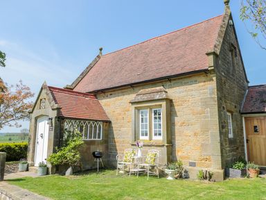 A stone cottage with a tiled roof outdoor chairs and table with flowers and grill at Fenwick Retreat at Fenwick Lodge Fenwick near Ponteland