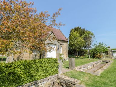 Exterior of a stone building with a red tiled roof surrounded by green bushes and trees at Fenwick Retreat at Fenwick Lodge Fenwick near Ponteland