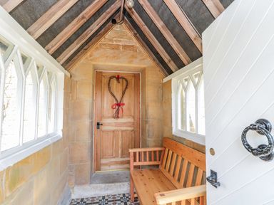 A porch area with wooden bench and a wooden door with a heart-shaped wreath at Fenwick Retreat at Fenwick near Ponteland