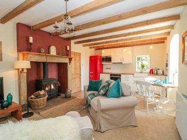 An open living room and kitchen with a beige sofa and wood stove at Fenwick Retreat at Fenwick near Ponteland