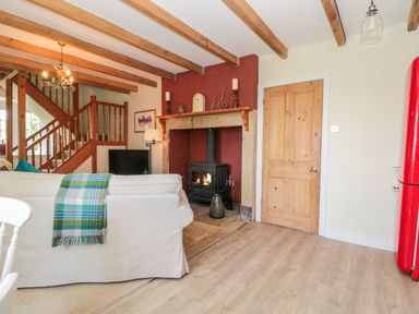 A living room with a beige sofa a fireplace wooden beams and a red refrigerator at Fenwick Retreat at Fenwick Lodge Fenwick near Ponteland