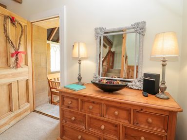 A wooden dresser with lamps a mirror and decorations beside a wooden door at Fenwick Retreat at Fenwick Lodge in Fenwick near Ponteland